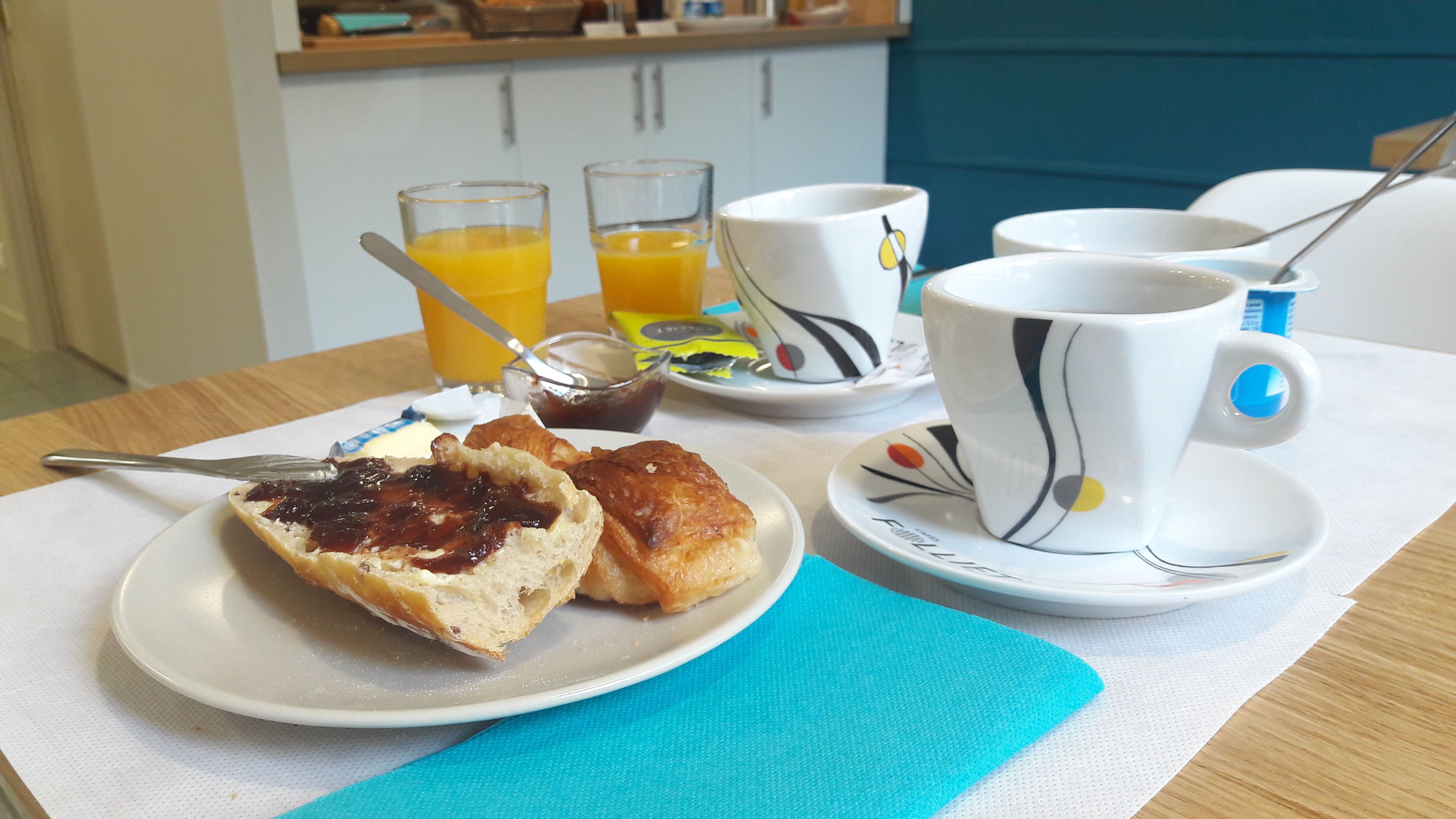 A breakfast setting with a plate of pastries, a cup of coffee, and glasses of orange juice.