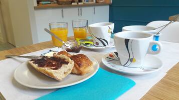 A breakfast setting with a plate of pastries, a cup of coffee, and glasses of orange juice.