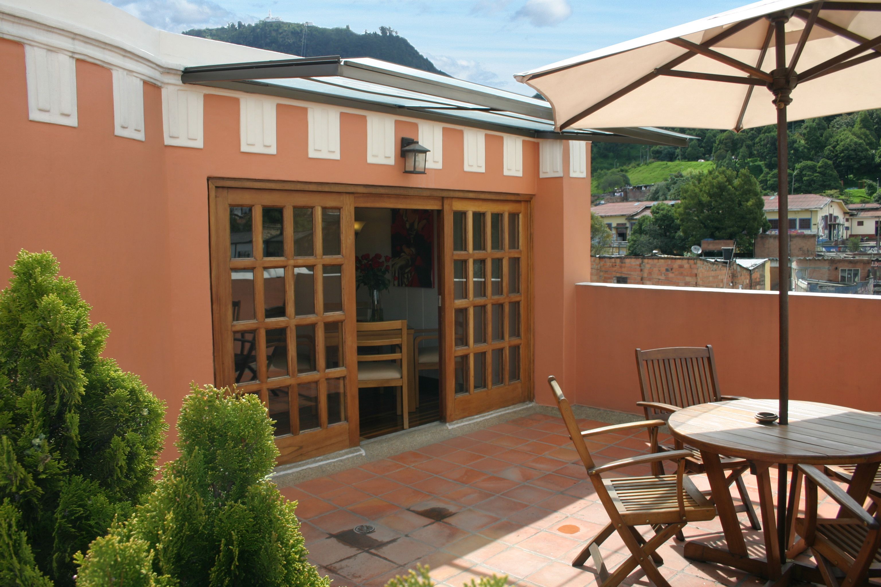 A patio with a round table and chairs, a large umbrella, and a sliding glass door leading to an interior space.