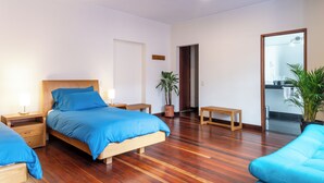 Un dormitorio moderno con una cama de madera, una mesita de noche, un banco, una planta en maceta y un espejo.