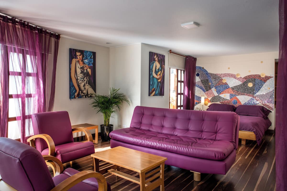 A modern living room with purple furniture, a wooden coffee table, and two paintings on the wall.
