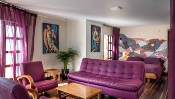 Una sala de estar moderna con muebles morados, una mesa de centro de madera y dos cuadros en la pared.