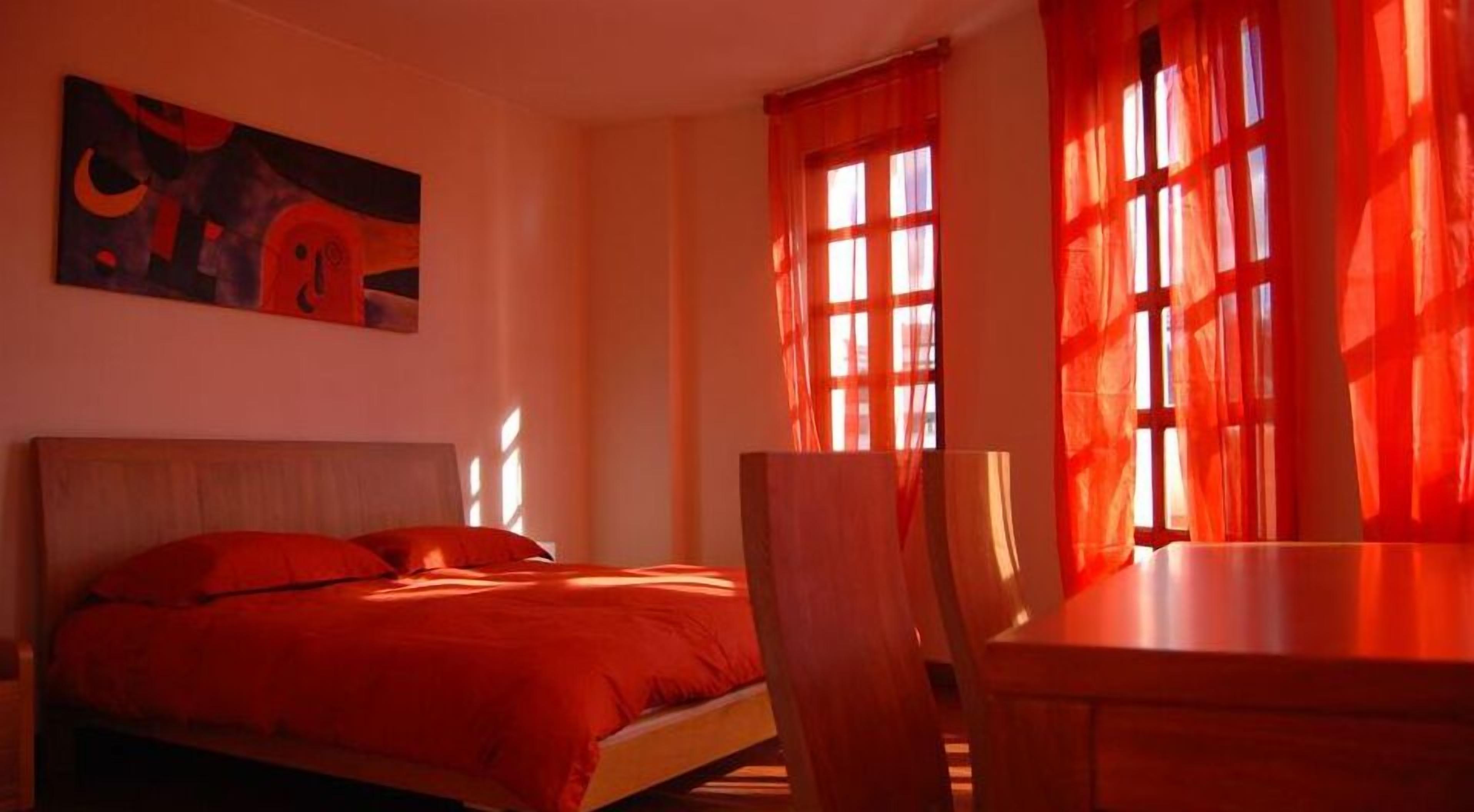 A room with a bed, a desk, and a painting on the wall.