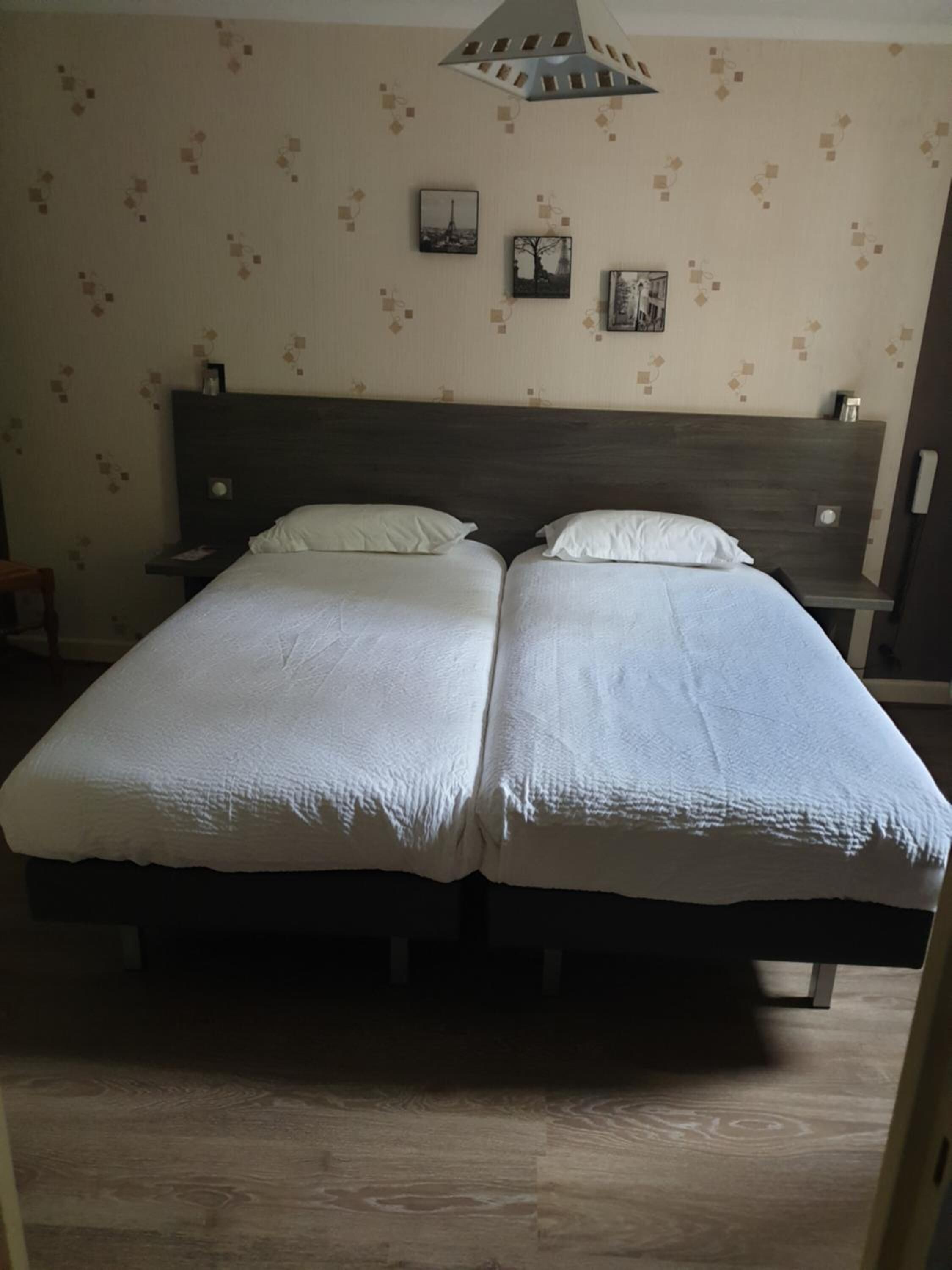 A double bed with a wooden headboard, two bedside tables, and a wall with patterned wallpaper.