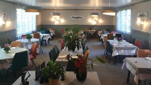 Un restaurant avec de nombreuses tables et chaises, dont certaines sont agrémentées de plantes.