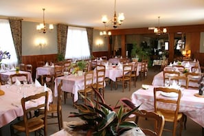 A dining area with multiple tables set for guests, each with a tablecloth and chairs. - Doubs Rivage (Charette)