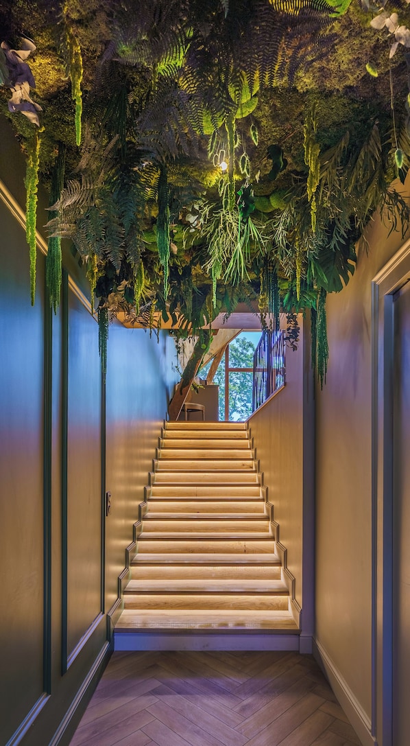 A staircase with wooden steps and a ceiling covered in artificial plants.
