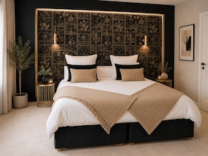 Una cama con estructura negra, ropa de cama blanca y cabecera decorativa con estampado floral.