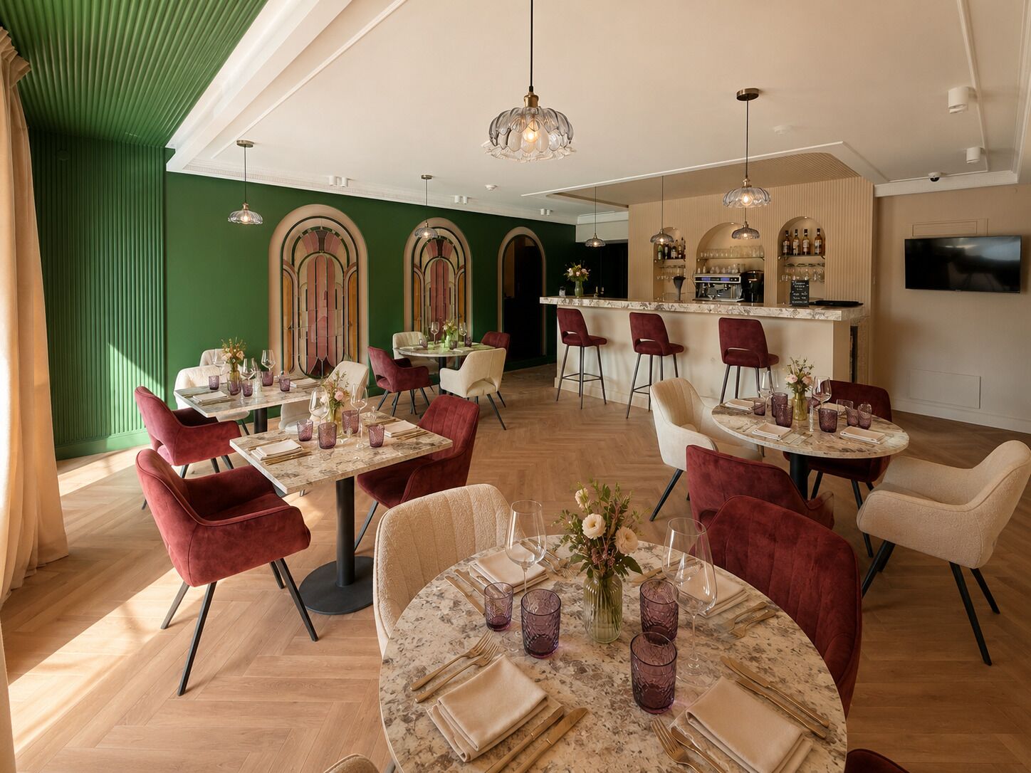 Un restaurant avec des tables rondes, des chaises rouges et un coin bar.