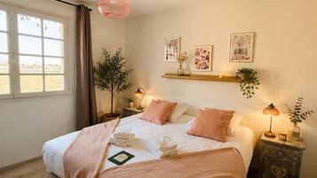 A bedroom with a bed, bedside tables, a window, and a hanging light fixture.