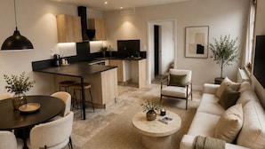 A modern living room with a dining area, kitchen, and a large window. - Hôtel Le Clos des Arts (Gevrey-Chambertin)