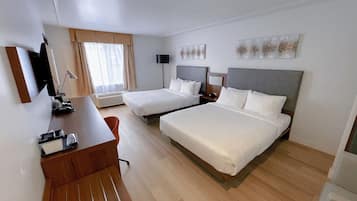 A hotel room with two beds, a desk, a chair, a TV, and a window with curtains.