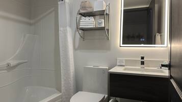 Un baño moderno con bañera, inodoro y tocador con espejo.