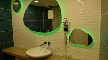 A bathroom with a round mirror, a sink, and a towel rack.