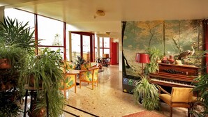 A spacious living room with a piano, chairs, and a large window.