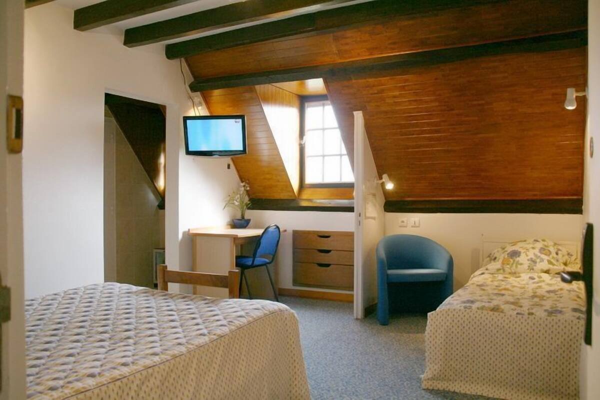 Una habitación con cama tipo litera, un escritorio con silla, un televisor y una ventana.