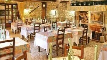A rustic dining area with stone walls, wooden tables, and chairs.