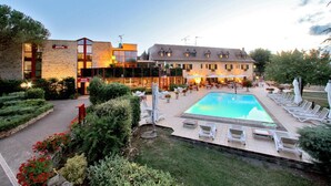 A hotel with a swimming pool, outdoor seating, and a garden area.