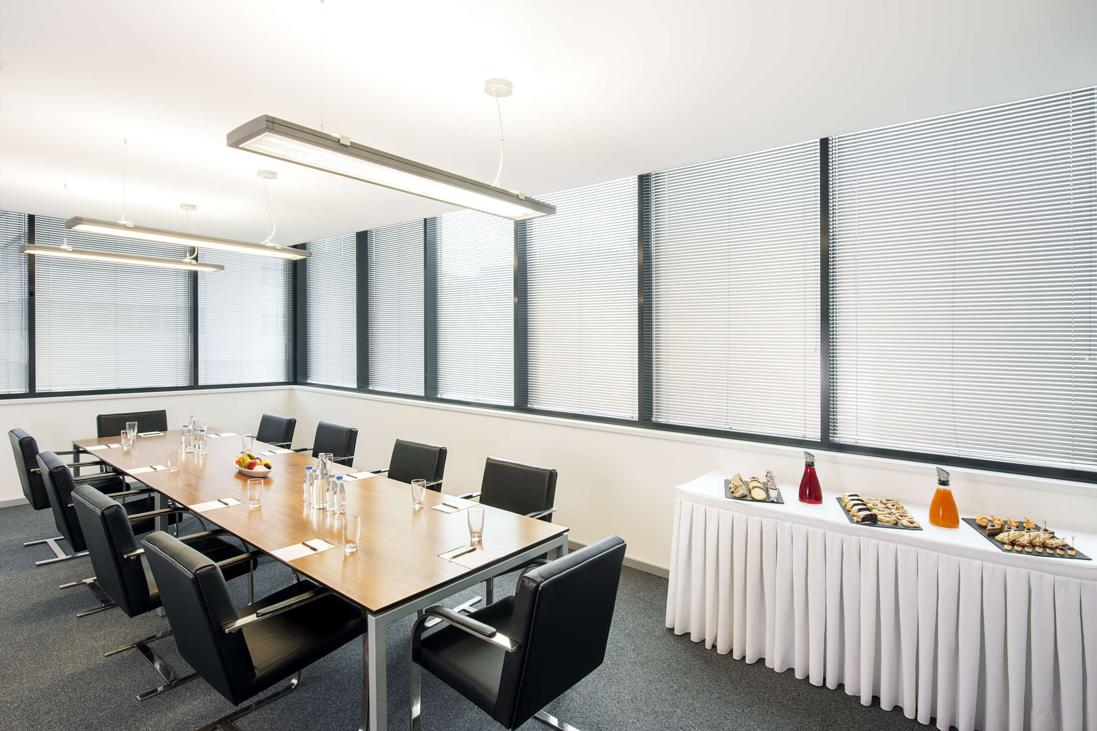 A conference room with a long table, chairs, and a buffet table with food items.