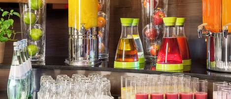 A juice bar with various fruit and vegetable juices, and a selection of glasses for serving.