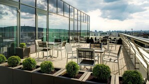 Een dakterras met terrasmeubilair en uitzicht over de stad.
