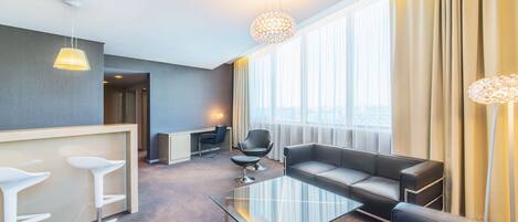 Una habitación de hotel moderna con una mesita de cristal, un sofá, un escritorio y una silla.