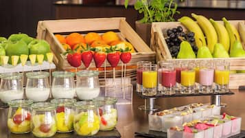 A breakfast buffet with various fruits, yogurt, and juices.