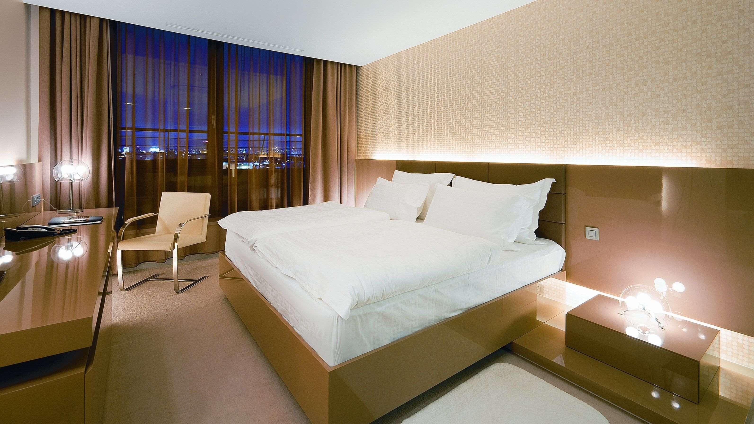 Une chambre d’hôtel moderne, dotée d’un grand lit, d’un bureau et d’une chaise.