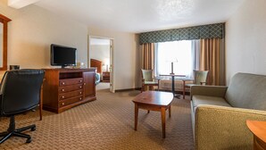 A hotel room with a desk, chair, sofa, and a television. - Baymont by Wyndham Fort Morgan (Fort Morgan)