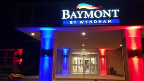 The exterior of the Baymont by Wyndham hotel with illuminated pillars and a glass entrance. - Baymont by Wyndham Fort Morgan (Fort Morgan)