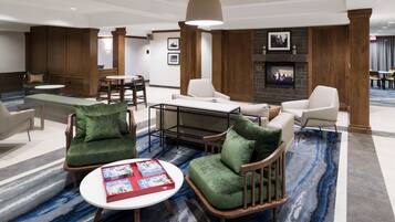 A modern hotel lobby with a fireplace, comfortable seating, and a coffee table with magazines.