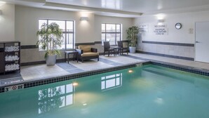 A swimming pool area with a lounge chair, a table, and potted plants.