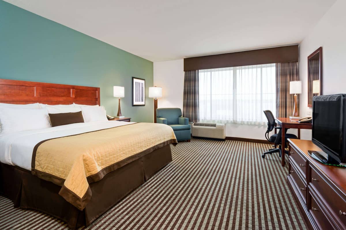 A hotel room with a large bed, a desk with a computer, a chair, and a TV.