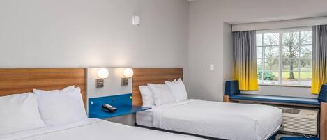 Ein Hotelzimmer mit zwei Betten, einem Holzkopfteil, einem Fenster mit Vorhängen und einem blauen Teppich.