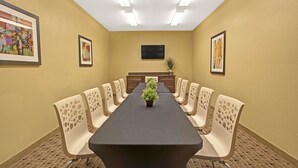 A conference room with a long table, beige chairs, a potted plant, and framed artwork on the walls. - Microtel Inn & Suites by Wyndham Cartersville (Cartersville)