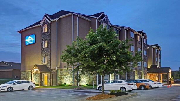 A multi-story hotel with a stone facade, a prominent sign, and a parking lot with several cars. - Microtel Inn & Suites by Wyndham Cartersville (Cartersville)