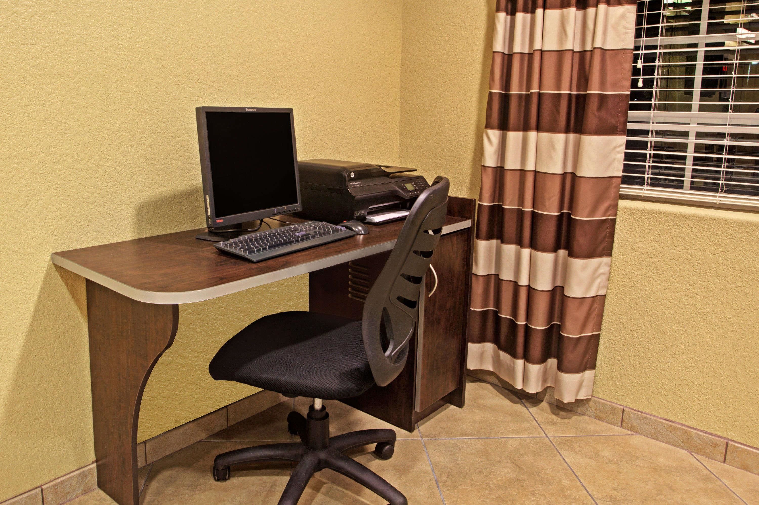 Un bureau d’angle équipé d’un bureau, d’un ordinateur, d’une imprimante et d’une chaise.