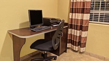 Escritório de canto com mesa, computador, impressora e cadeira.
