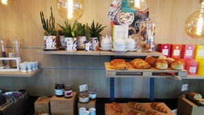A cafe with a wooden counter displaying pastries, jars of jam, and a variety of tea and coffee containers. - Residhome Asnières (Asnieres-sur-Seine)