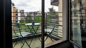 A balcony with a table and chairs, overlooking a residential area with multiple buildings. - Residhome Asnières (Asnieres-sur-Seine)