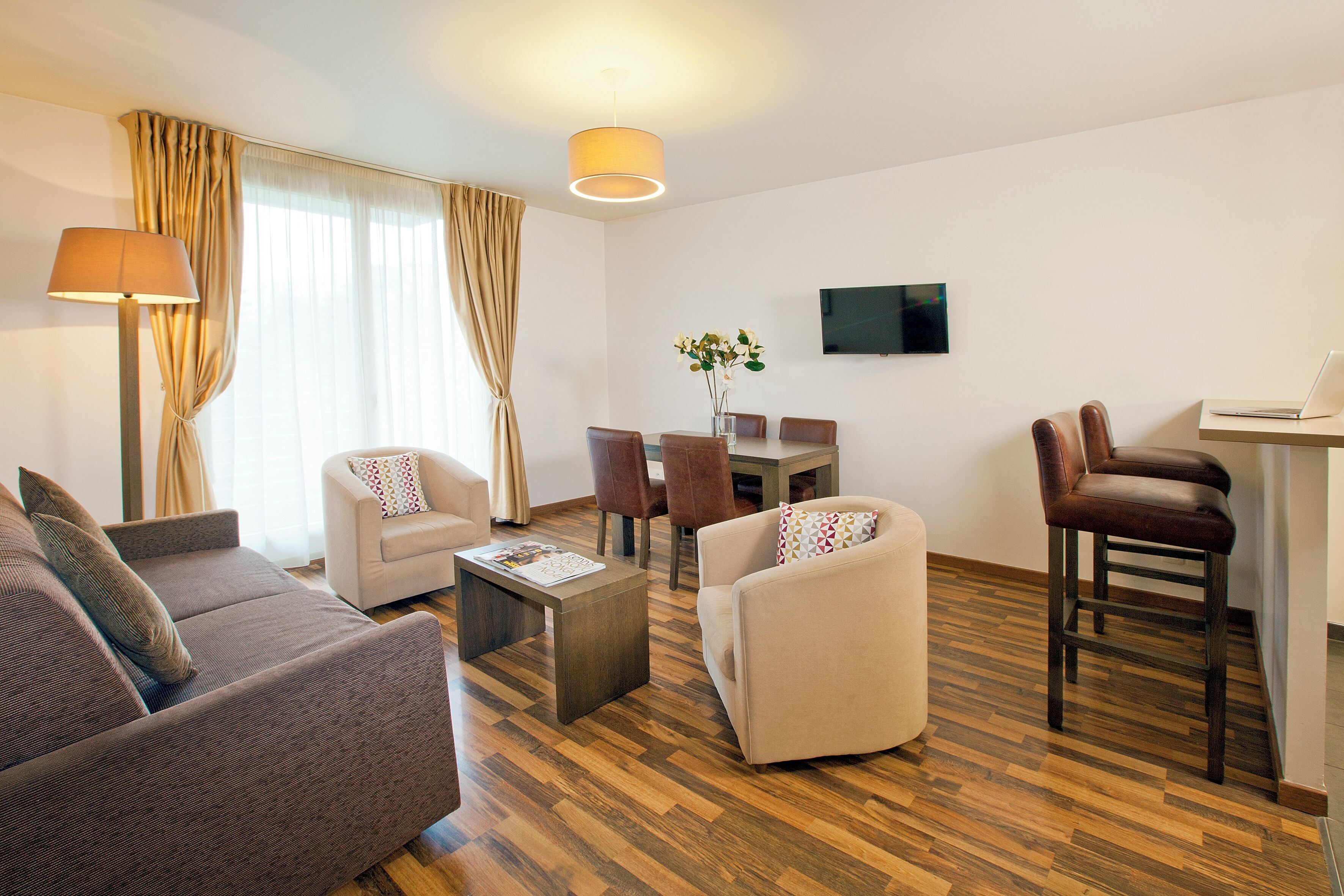 Una sala de estar moderna con un sofá, sillones, una mesa de centro y un comedor con sillas y una mesa.
