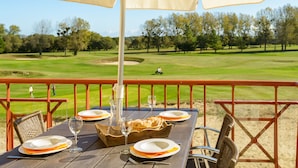A dining table set outdoors with a view of a golf course in the background. - Résidence Lagrange Vacances Cap Green (Frehel)