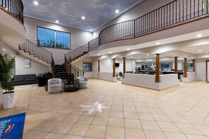 A spacious lobby with a staircase, seating area, and a reception desk.