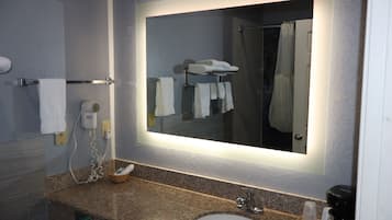 A bathroom with a granite countertop, a white sink, a mirror, and a shower curtain.