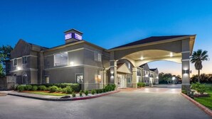 A two-story building with a covered entrance, a visible sign, and a well-maintained lawn. - Baymont by Wyndham Texas City (Texas City)