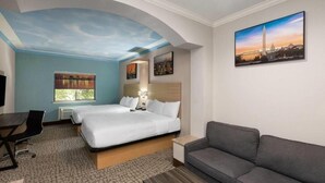 A hotel room with a bed, a sofa, a desk, and a TV. - Baymont by Wyndham Texas City (Texas City)