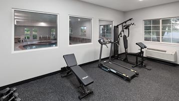 Un gimnasio con equipo de ejercicio, incluyendo una cinta de correr, banca y máquinas de pesas.