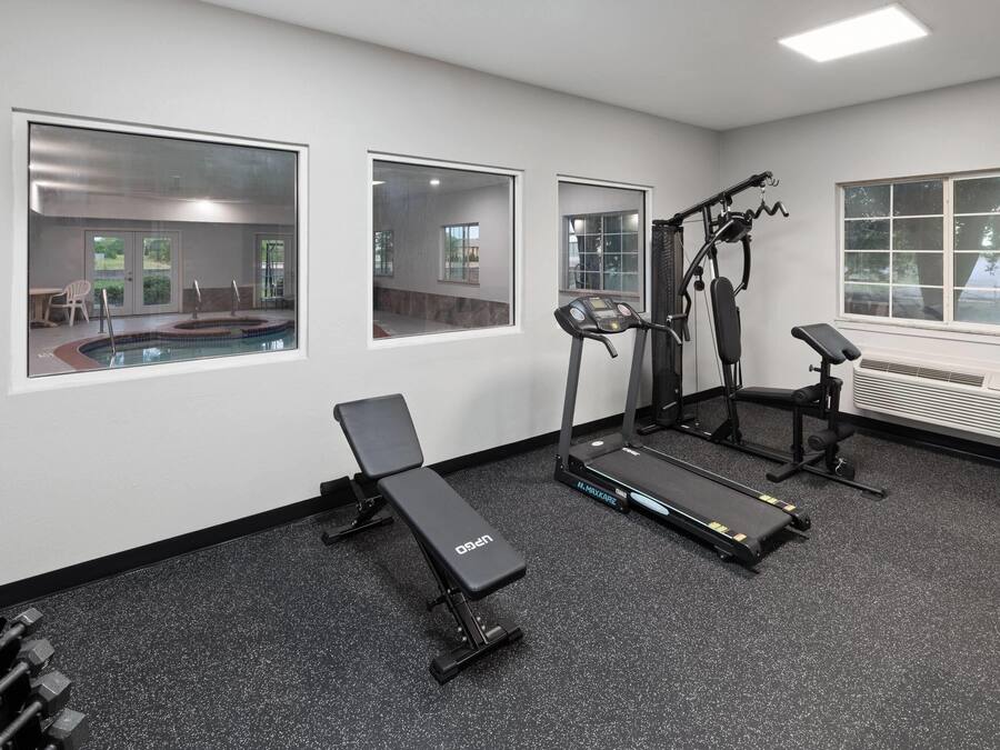 Un gimnasio con equipo de ejercicio, incluyendo una cinta de correr, banca y máquinas de pesas.