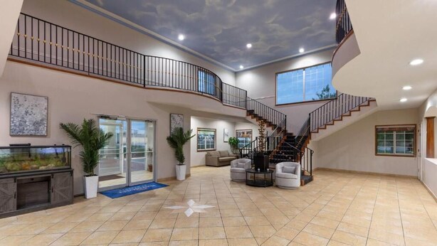A spacious interior with a curved staircase, a large fish tank, and a modern ceiling design. - Baymont by Wyndham Texas City (Texas City)