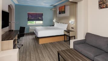 Habitación de hotel con cama, escritorio, sofá, televisor, ventana con vista panorámica de la ciudad y techo decorado con un diseño pintado.